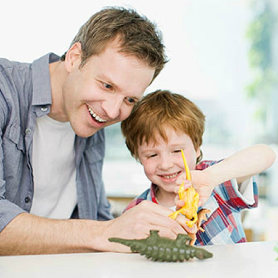 un adulto sorridente gioca con un bambino sorridente con i dinosauri 